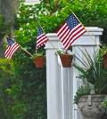 3 little American flags on white fence